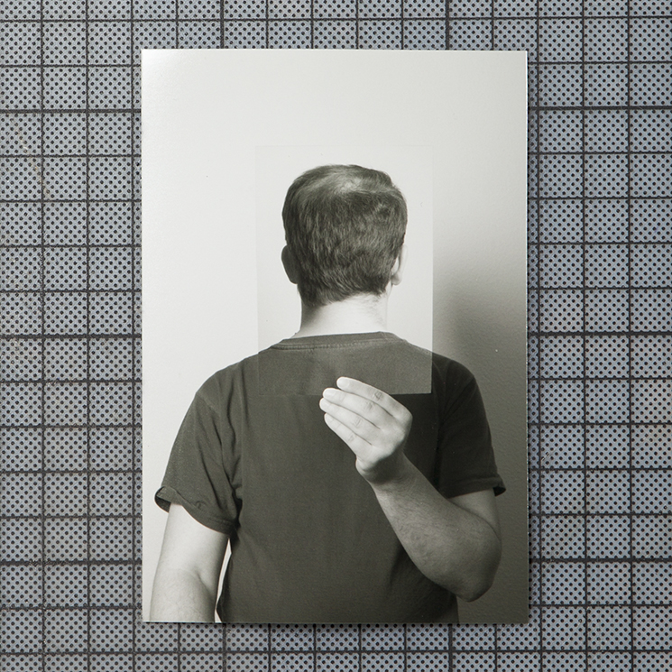 the photograph shows a man holding a photograph of his own head from the back just at the position his head would be.