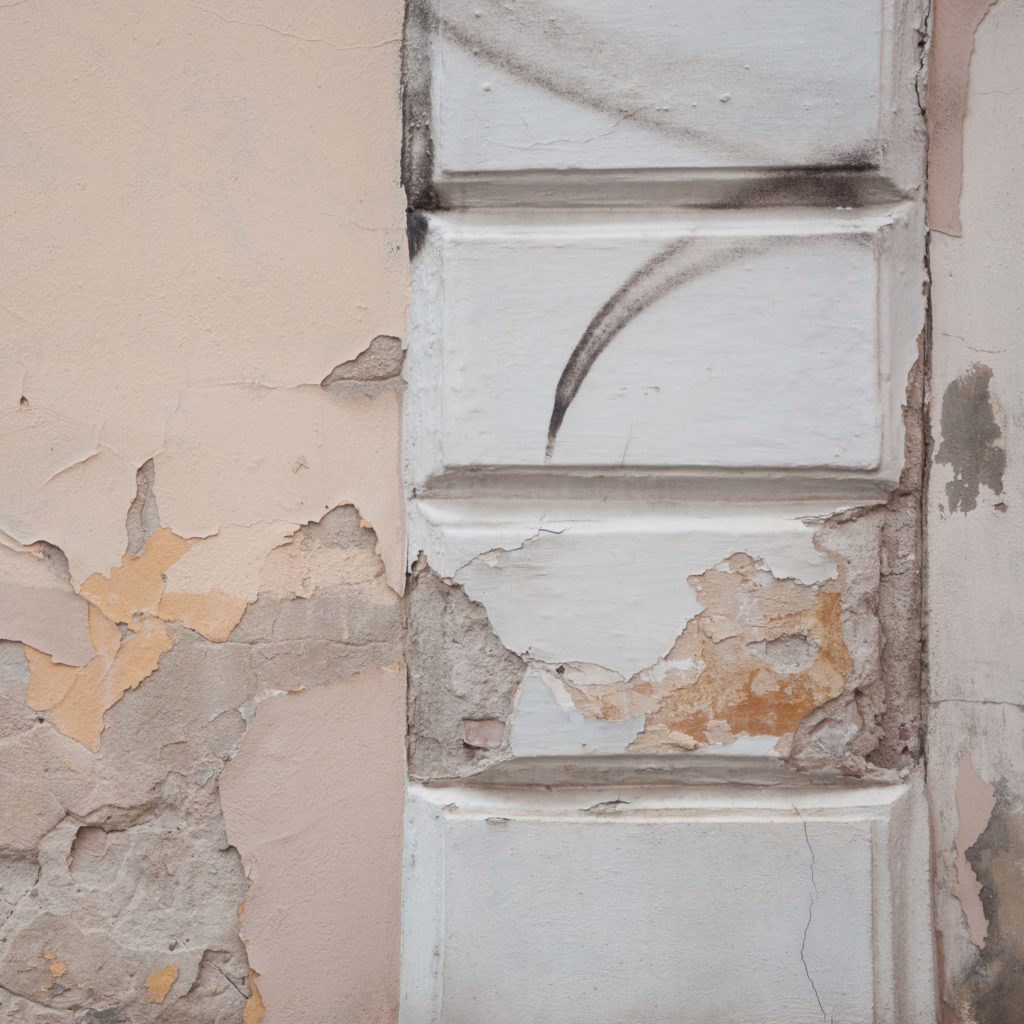 the photograph shows an old and damaged edge of a house which is covered with cracks
